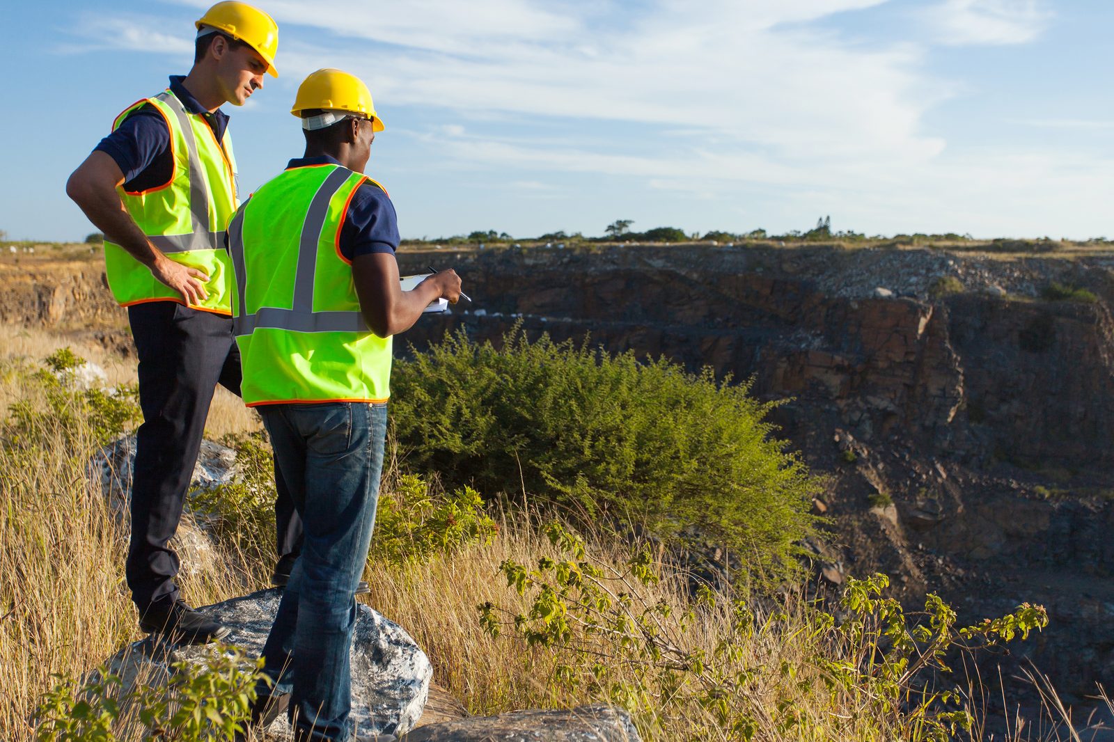Two operators reviewing a plan at the rim of an open-cast mine